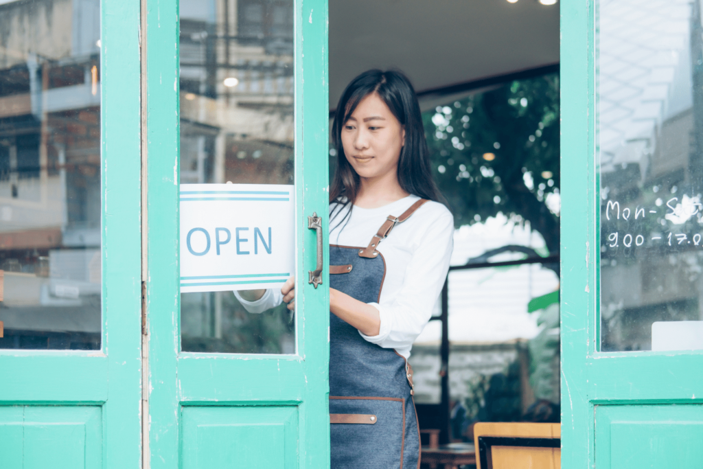 Female business owner proudly opens up her shop for the day.